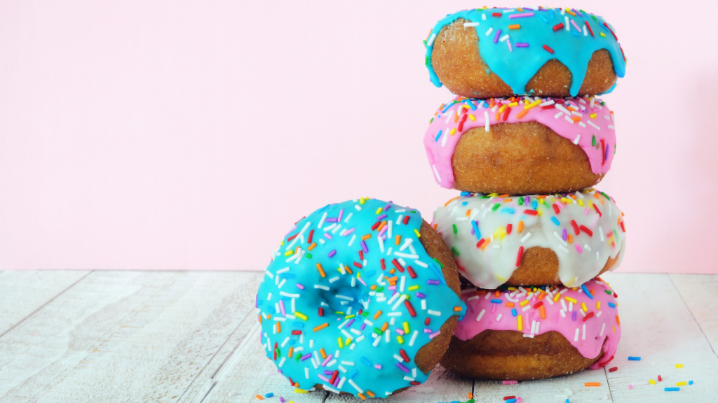 Colorful donuts on a white table with a pink background