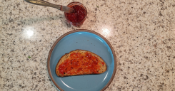 Strawberry jam - image of sourdough toast with strawberry jam and the jar in the frame next to the plat with a knife in it